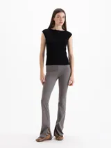 Pantalón Margot de microfibra negra, de tiro alto y silueta ajustada con botamangas acampanadas y tajos laterales.