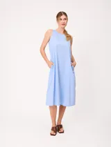 Vestido midi sin mangas de corte recto y holgado, color beige, con cuello redondo y bolsillos laterales.