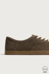 Zapatilla deportiva barefoot fabricada en piel con acabado serraje de color marrón, con cordones en contraste y suela fina de goma.