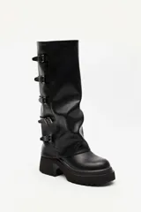 Bota alta marrón de diseño slouchy con plataforma track y múltiples hebillas metálicas decorativas en la parte lateral exterior de la caña.