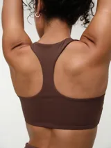 Top deportivo negro con espalda nadadora, copas removibles y detalle de logo sutil en el elástico inferior.