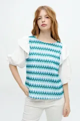 Blusa con estampado geométrico en tonos celeste y blanco, con mangas cortas abullonadas de tela lisa blanca y volados en los hombros.