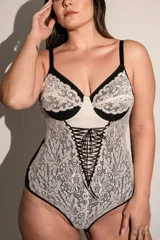Body de lycra y puntilla elastizada color crudo con detalles en negro. Tiene aro, breteles regulables y detalle de cintas cruzadas en el frente.
