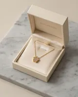 Collar de cadena fina con dije en forma de flor con incrustaciones de circonias, con baño de oro.