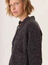 Saco de lana color marrón, de tejido grueso, con cuello redondo y botones frontales. Presenta mangas raglán con detalle de punto acanalado y bolsillos delanteros tipo parche.