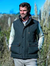 Chaleco acolchado de color azul oscuro con diseño de rombos, cuello alto, cierre frontal con botones a presión y bolsillos delanteros con solapa y detalles en contraste.