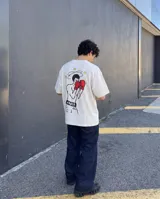 Remera de corte oversize color beige, con estampa estilo pixel art en la espalda que representa a un boxeador con guantes rojos y estrellas alrededor de la cabeza.
