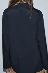 Camisa fluida de viscosa con cuello solapa de muescas, manga larga con puños y bolsillo de plastrón en el pecho. Cierre frontal con botones.