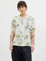 Camisa de manga corta con cuello resort y calce relajado. Confeccionada en viscosa, presenta un estampado floral en tonos azules y verdes sobre fondo color crema.