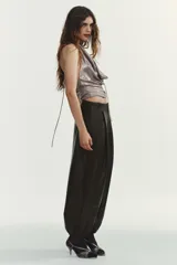 Pantalón jogger de tiro medio confeccionado en tejido efecto piel. Presenta pliegues en el delantero, bolsillos laterales, falsos bolsillos de vivo en la parte posterior y bajo acabado en elástico. Cierre frontal con cremallera, botón interior y gancho metálico.