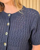Cardigan calado de manga corta, tejido en punto con cierre frontal de botones y cuello redondo.