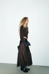 Falda midi negra de tejido satinado, corte recto y tiro alto con cintura elástica.