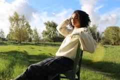 Sweater artesanal de punto en color marfil, confeccionado en pura lana merino. Presenta un amplio canesú decorado con trenzas, bodoques y calados, de mangas largas abullonadas y cuello redondo.
