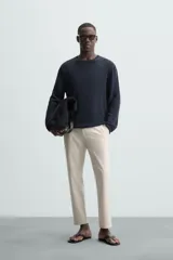 Pantalón chino de corte slim fit, confeccionado en tejido elástico. Presenta bolsillos frontales, bolsillos traseros de vivo con botón y cierre frontal con cremallera y botón.