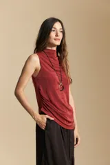 Top sin mangas de color negro con cuello alto y diseño drapeado en el frente. Confeccionado en una tela suave con acabado levemente satinado y silueta fluida.