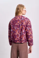 Campera bomber corta color bordó con estampado abstracto en tonos naranja y lila, cierre frontal y mangas largas abullonadas.