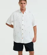Camisa de manga corta color blanco con estampa de mini palmeras en negro, corte relaxed y cierre frontal de botones con efecto carey.