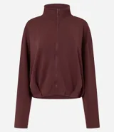 Campera de modal color marrón, con cuello alto, cierre frontal completo y diseño con pliegues en el ruedo. Presenta mangas largas y un calce holgado.