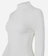 Blusa cropped de punto chenille color negro, con cuello alto y mangas largas raglán. Presenta una textura acanalada y pequeños puntos brillantes aplicados en el frente.