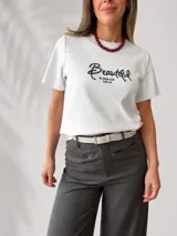 Remera azul marino de manga corta y corte clásico, con estampa bordada con la palabra "Beautiful" en el frente. Incluye un pañuelo de cuello con estampado a cuadros en tonos oscuros.