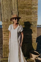 Vestido largo color crudo, de corte recto, con escote en V y mangas cortas. Presenta detalle de bordado dorado en cuello, mangas y laterales.