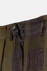 Pantalón de tiro alto con diseño fluido y estampado de cuadros en tonos oscuros. Presenta pliegues frontales, bolsillos delanteros con solapa y cierre frontal con cremallera, botón y ganchos metálicos.