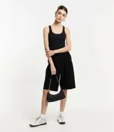Musculosa básica de calce ajustado confeccionada en tejido rib acanalado. Presenta escote redondo y breteles medios, ofreciendo un diseño versátil y cómodo.