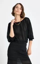 Blusa negra de encaje con hombros caídos, mangas tres cuartos con puños ajustados y diseño de paneles verticales texturizados.
