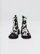 Bota tipo chelsea de cuero vacuno en color rojo con estampado floral grabado en negro. Presenta paneles laterales elásticos, suela de plataforma y taco cuadrado en color negro.