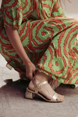 Sandalias plateadas con tira ancha sobre los dedos, tira fina con hebilla al tobillo y taco cuadrado bajo.