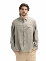 Camisa de manga larga color gris topo, con cuello abotonado, dos bolsillos frontales con solapa y cierre de velcro, mangas con opción de arremangado y abertura en la espalda para ventilación.