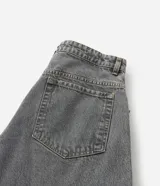 Pantalón de jean estilo baggy balloon, de corte holgado con volumen en las piernas y cintura fija con trabillas. Presenta costuras a contratono y detalle de cadena metálica lateral.