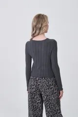 Remera de manga larga confeccionada en viscosa, con diseño entallado y cuello redondo a la base. Presenta una textura acanalada y terminaciones con ondas en los puños y el ruedo.