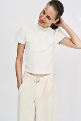Top de punto color blanco, de cuello redondo y manga corta abullonada.