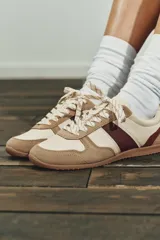 Championes de estilo running con diseño de paneles combinados en cuero y serraje. Presenta una base en tono crema con detalles en color bordó y refuerzos en gamuza color tostado. Cuenta con cierre mediante cordones y punta redonda.