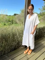 Vestido largo de lino color azul marino, con escote en V y mangas cortas amplias. Presenta un corte relajado y bolsillos laterales.