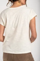 Remera de algodón flame color blanco marfil, con cuello redondo amplio y mangas cortas holgadas.