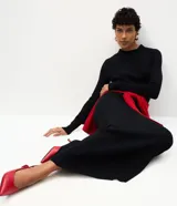 Vestido midi de punto acanalado color bordó, con cuello redondo y mangas largas. Presenta un diseño ajustado en el torso que se extiende hacia una falda con caída fluida.