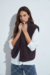 Chaleco de corderito color marrón oscuro, con cierre frontal completo, cuello alto y bolsillos laterales.