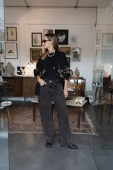 Pantalón de jean de corte recto y tiro medio, con un acabado de teñido ácido en tonos oscuros. Presenta bolsillos traseros con bordados decorativos en color negro y una etiqueta de cuero en la cintura.