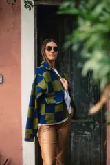 Sobre camisa de paño con diseño a cuadros en tonos azul y verde, cuello clásico, cierre frontal con botones y bolsillos grandes frontales.