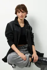 Campera negra de polar y nylon con cuello alto, cierre frontal y bolsillos laterales.