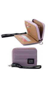 Billetera corta de diseño capitoneado con cierre perimetral y solapa frontal. Cuenta con compartimentos internos para tarjetas y billetes, e incluye una correa de mano desmontable.