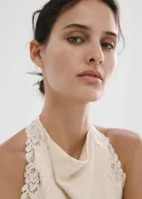 Top de algodón color crudo, con cuello halter y delicados ribetes de encaje en las sisas y el ruedo inferior.