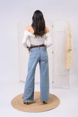 Remera blanca de manga larga con escote off-shoulder y diseño fruncido en el escote.