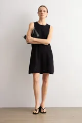 Vestido corto negro sin mangas, de corte recto y escote redondo, con detalles de tejido calado en el ruedo.