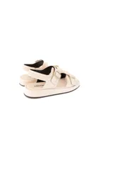Sandalias planas color off-white, con múltiples tiras ajustables con hebillas metálicas plateadas y plataforma baja.
