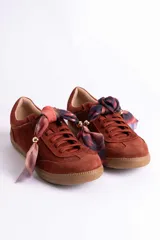 Zapatillas de gamuza color marrón con suela de goma color caramelo. Presentan cordones al tono y un detalle decorativo de pañuelo estampado atado en los laterales con esferas metálicas doradas.