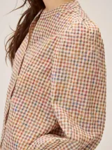 Camisa de color crema con bordados florales, cuello mao, cierre frontal con botones y mangas largas abullonadas con volados en los hombros.