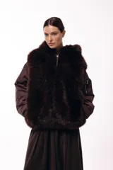 Campera de invierno con frente de piel sintética y capucha integrada, combinada con mangas acolchadas de estilo puffer en color marrón oscuro.